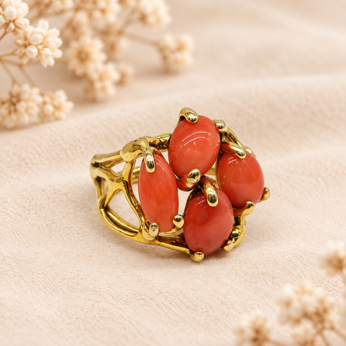 Primo piano dell’anello regolabile con quattro cabochon di corallo rosa naturale e montatura traforata in Argento 925 placcato oro giallo
