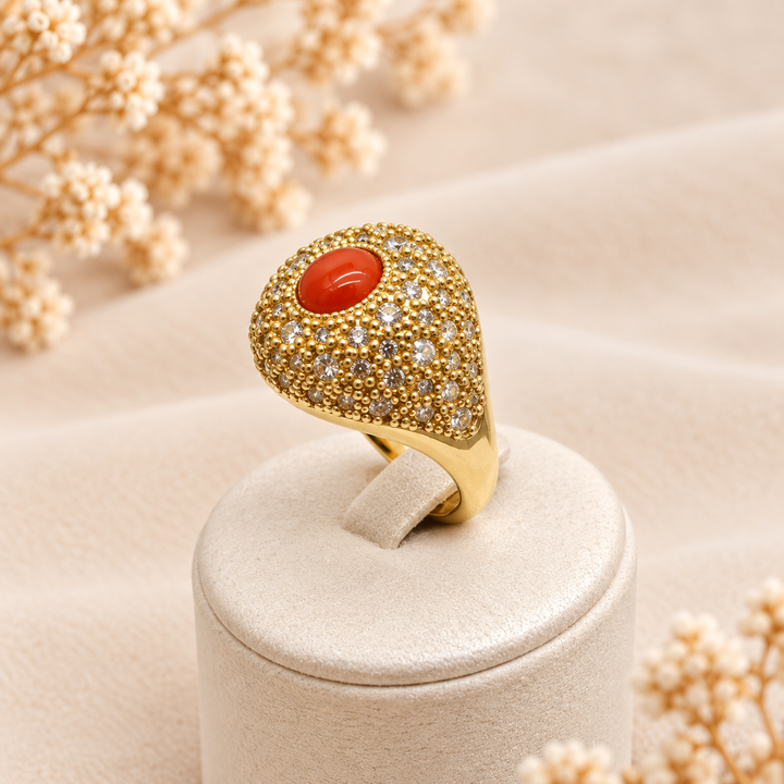 Anello regolabile dorato con cabochon di corallo rosso naturale del Mediterraneo e pavé di zirconi, fotografato su espositore