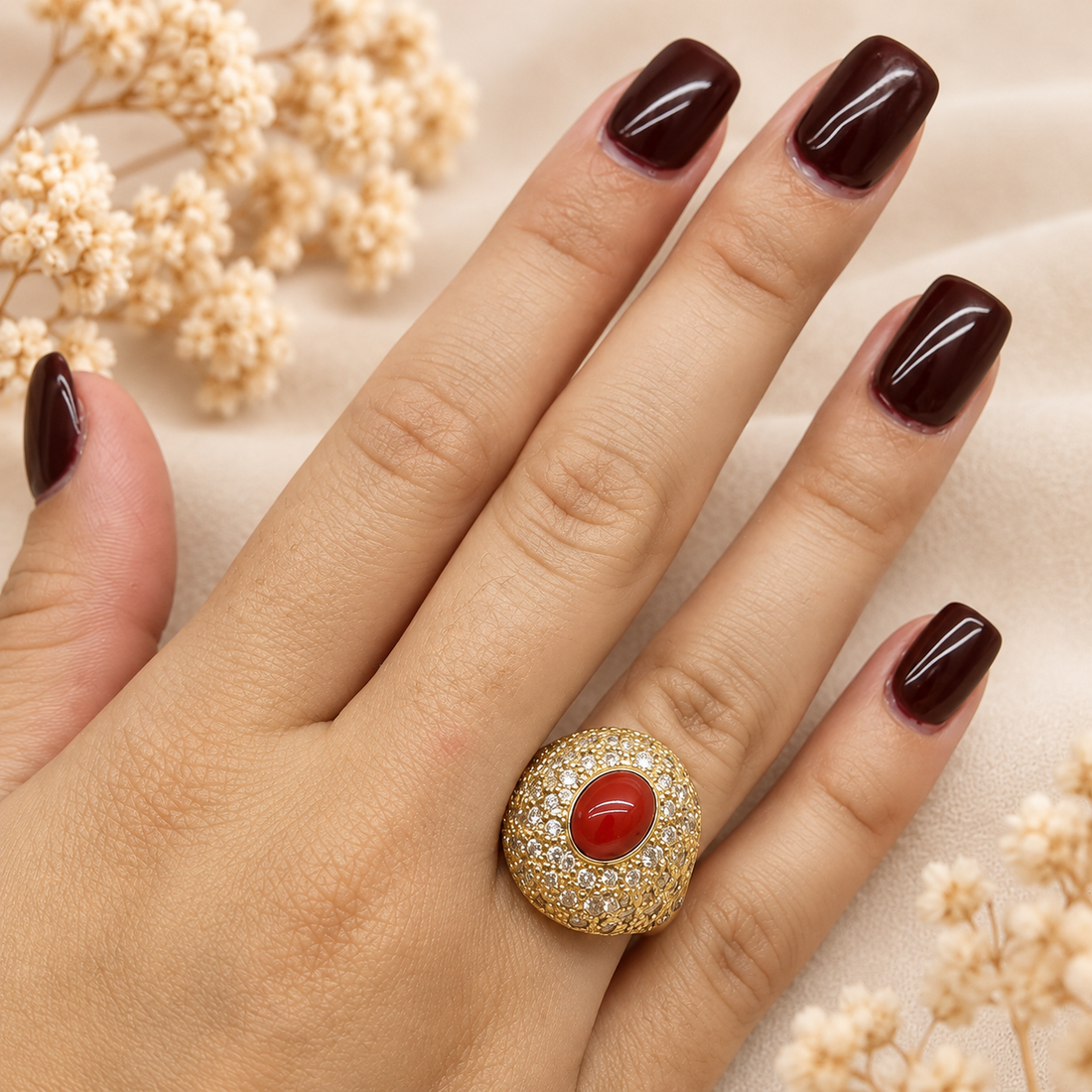 Anello regolabile dorato con cabochon di corallo rosso naturale del Mediterraneo e pavé di zirconi indossato sulla mano
