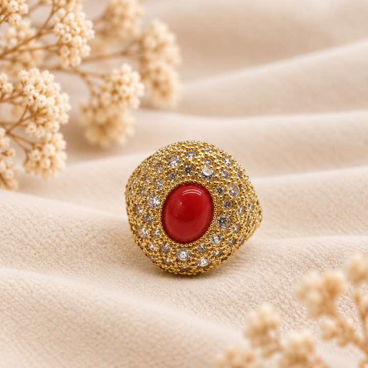 Vista frontale dell’anello dorato con cabochon centrale di corallo rosso naturale del Mediterraneo circondato da pavé di zirconi