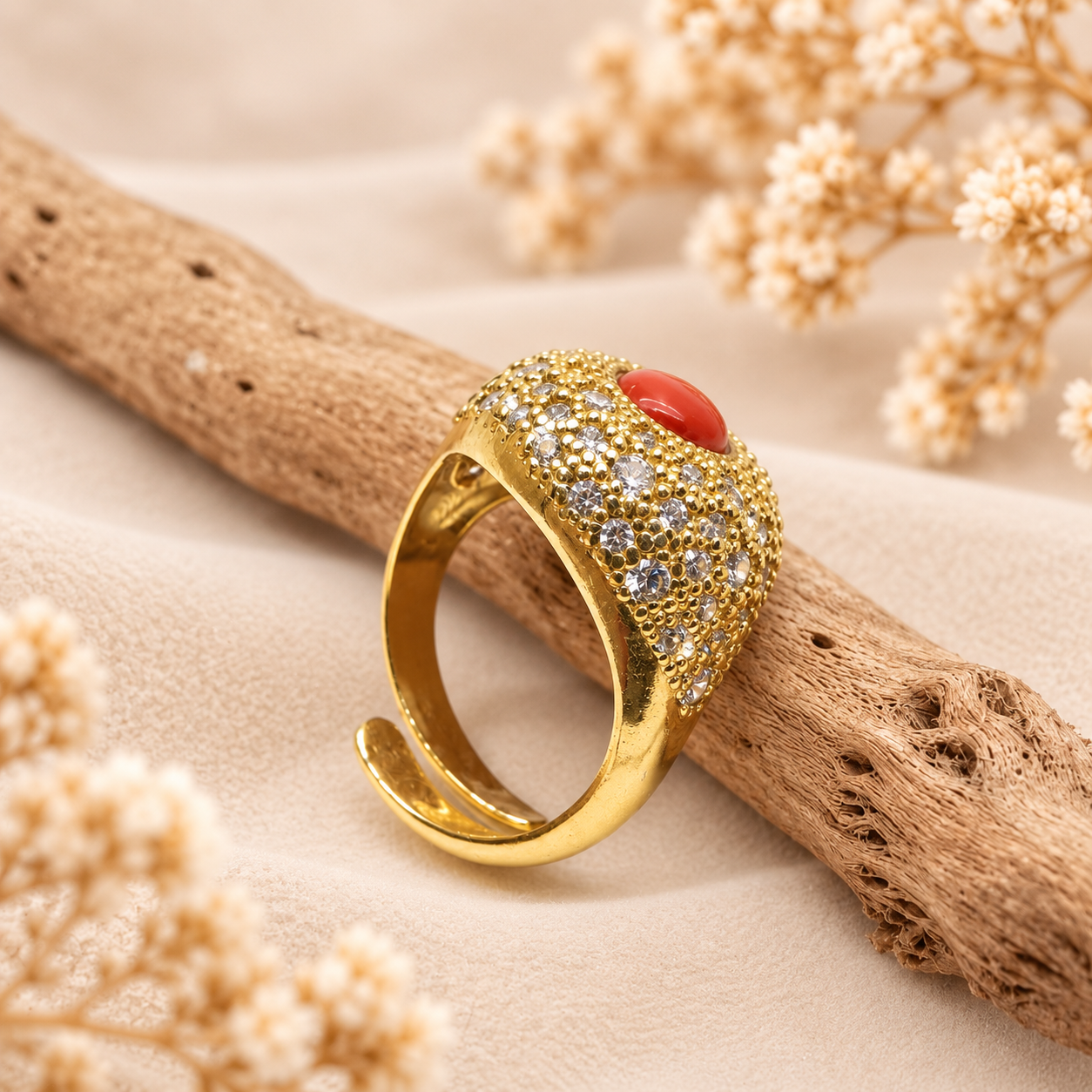 Vista laterale dell’anello dorato regolabile con cabochon di corallo rosso naturale e pavé di zirconi