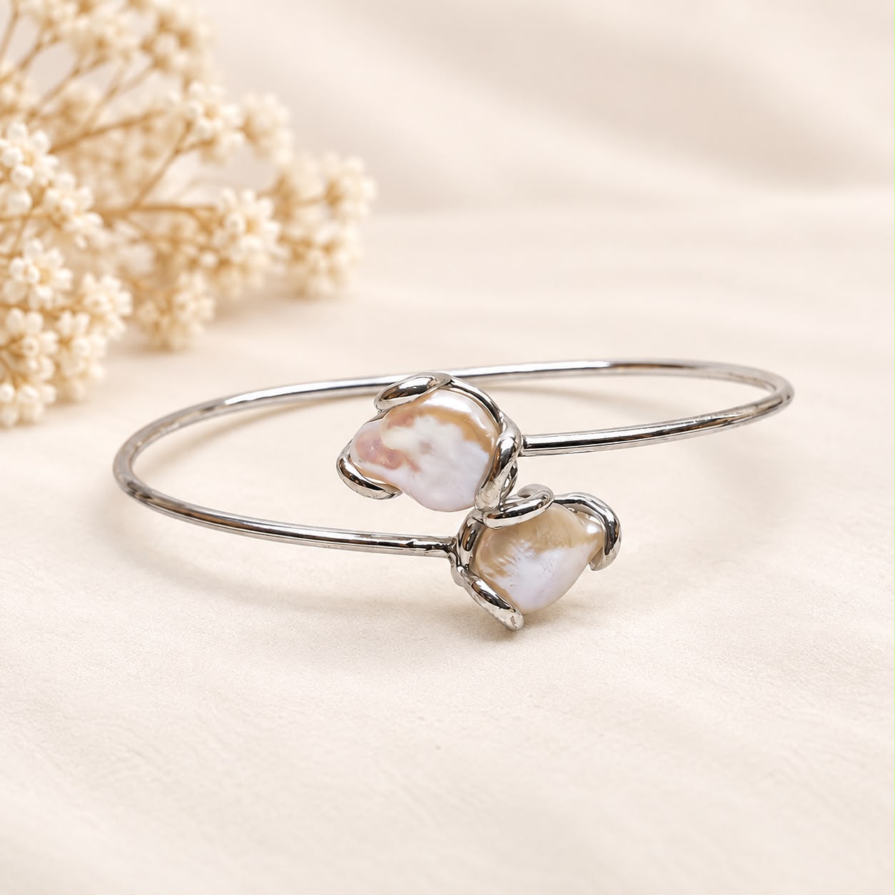 Bracciale flessibile in argento 925 rodiato con due perle barocche naturali d’acqua dolce e montatura aperta contrariè.