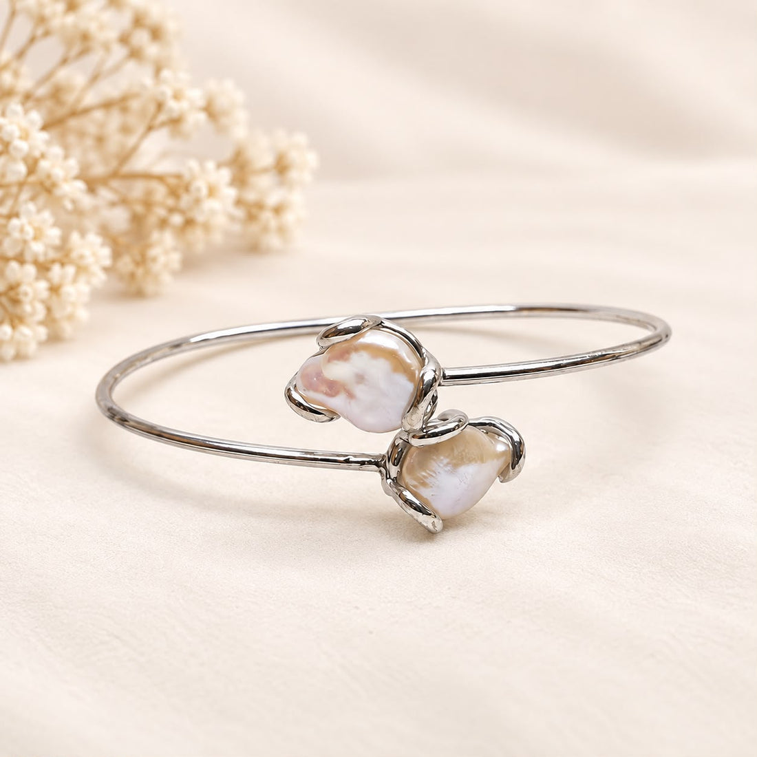Bracciale flessibile in argento 925 rodiato con due perle barocche naturali d’acqua dolce e montatura aperta contrariè.
