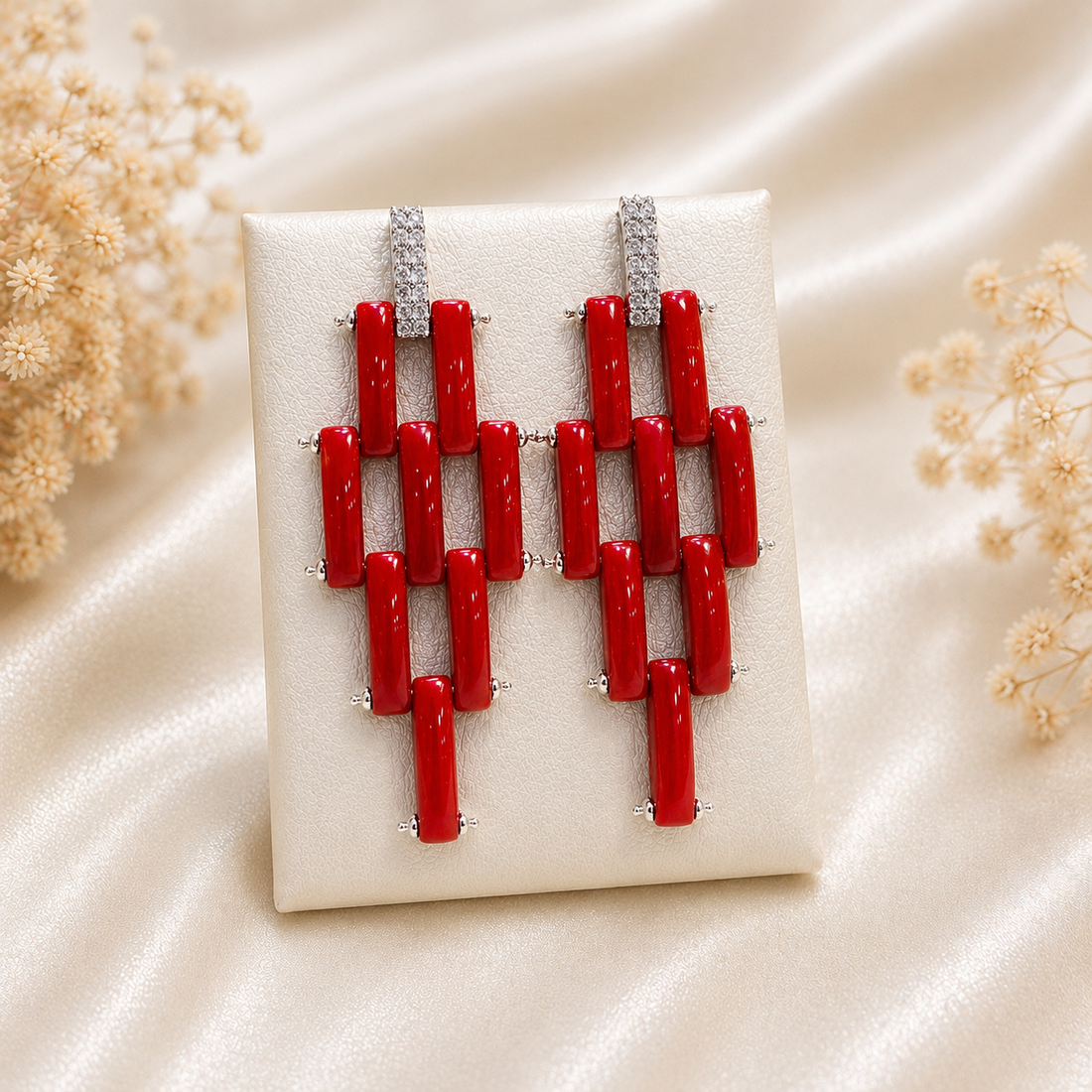 Orecchini modello Cartier in Argento 925 rodiato con fascette di Corallo Rosso Naturale del Mediterraneo e pavé di zirconi, fotografati su espositore.