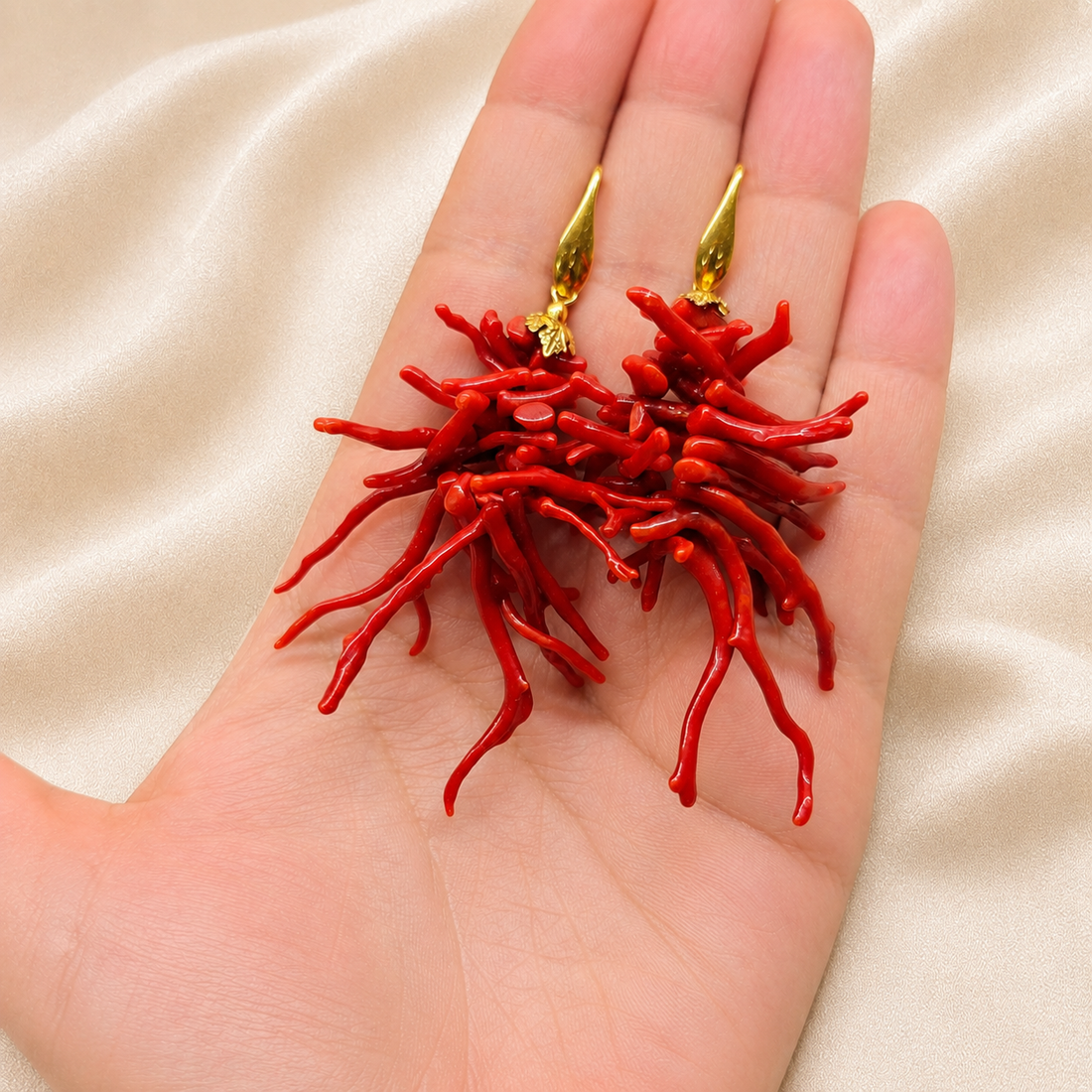 Orecchini pendenti a ciuffo con rametti di corallo rosso naturale del Mediterraneo e Argento 925 dorato mostrati nella mano